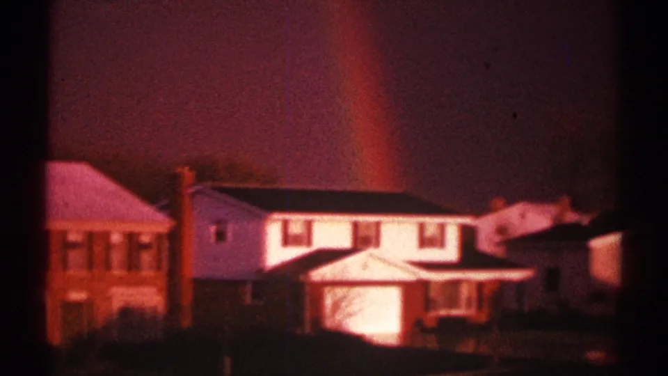 Clarendon Hills residential exterior with two-story homes, warm window light, and a faint rainbow in the evening sky.