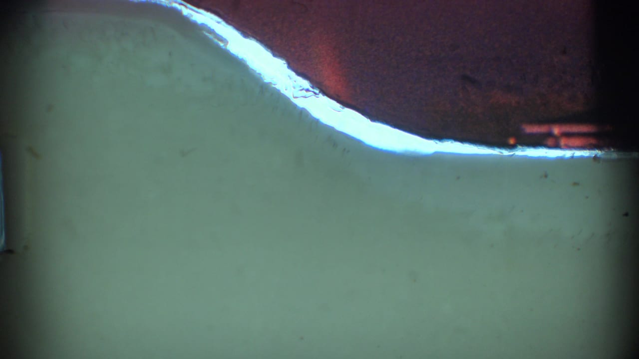 Dim green-blue frame with a bright curved edge near the upper left and dark film borders.