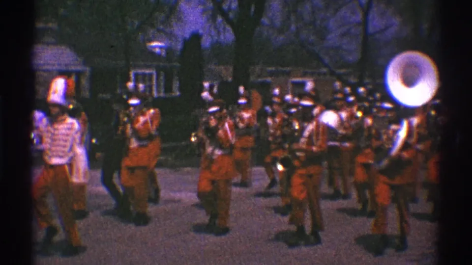 Clarendon Hills 1969 home-movie frame showing the band passing close to the camera, with sousaphone and brass players prominent.