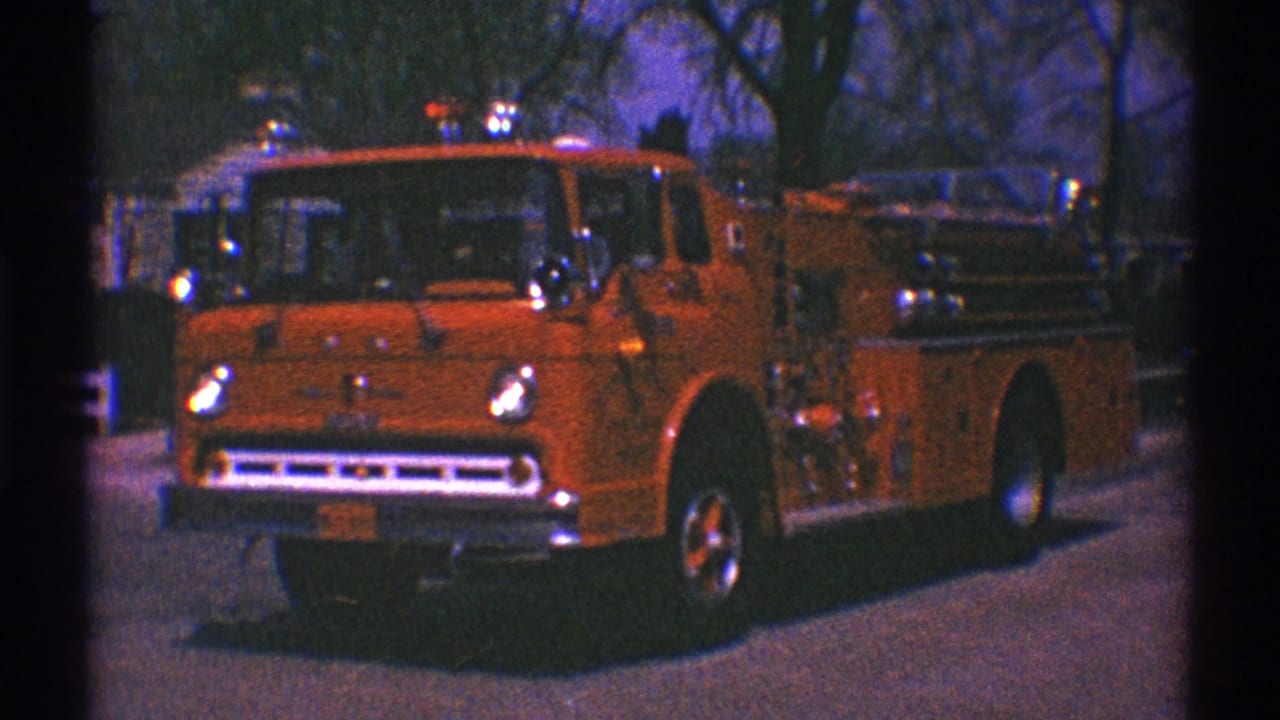 The fire truck passes near the curb in Clarendon Hills, with chrome lights and grille visible against a residential street background.