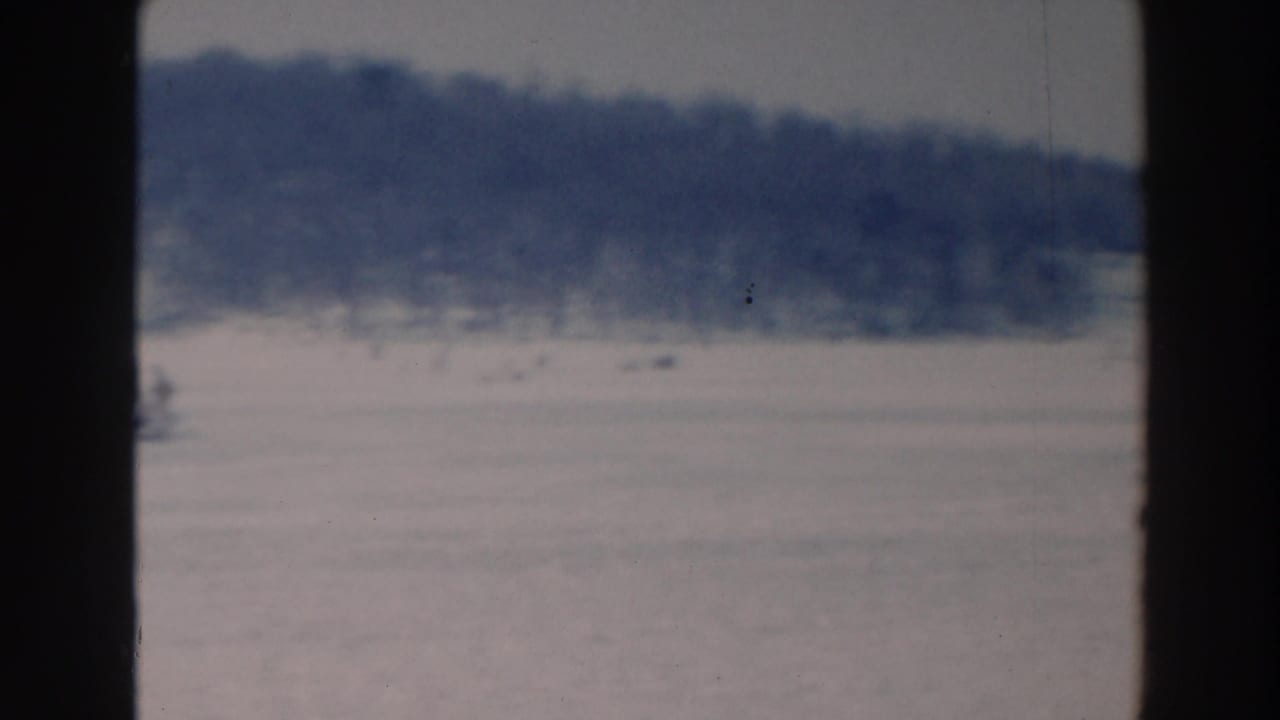 Blurred winter lake view with distant figures on snow-covered ice.