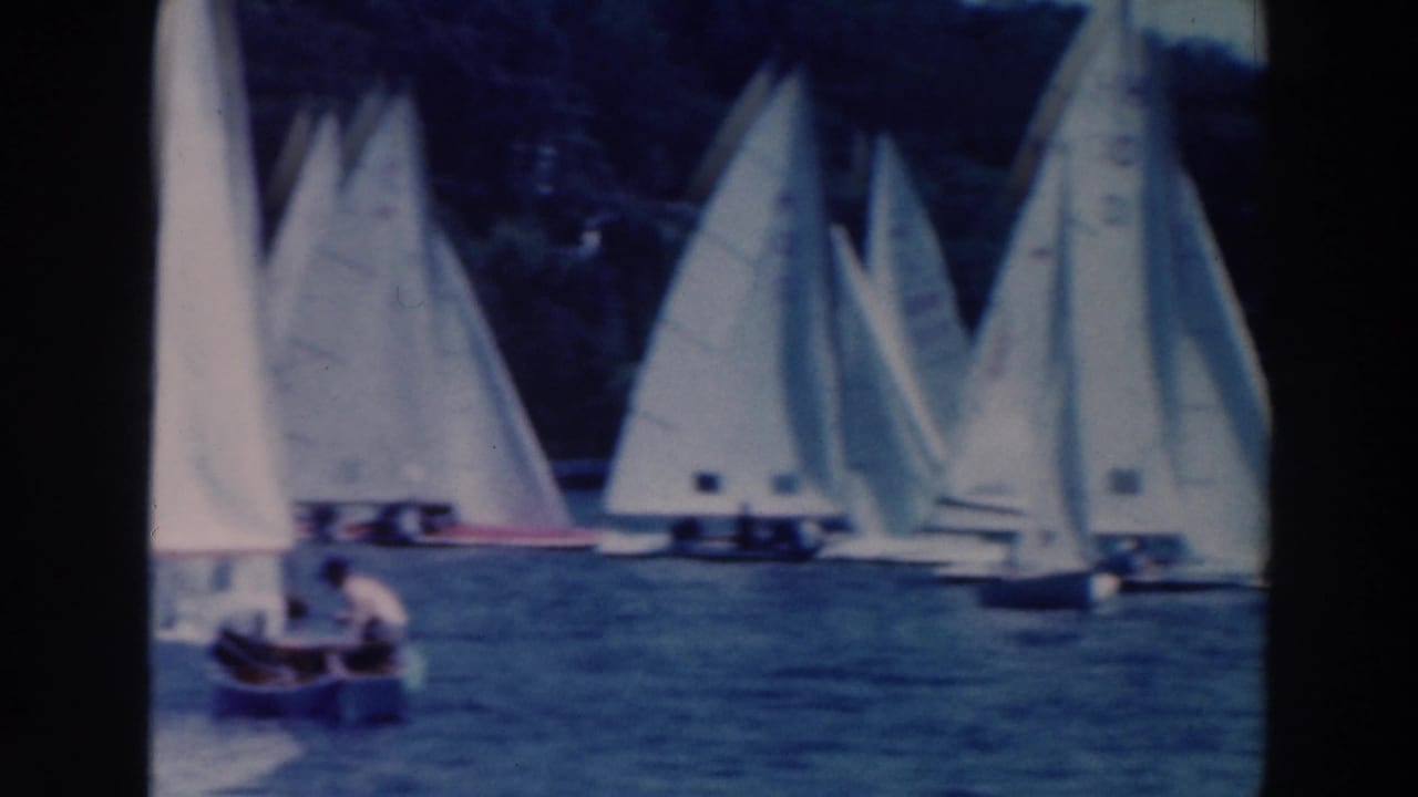 1964 Tustin, Wisconsin sailing scene with white sails across the water and a small foreground boat carrying a visible person.