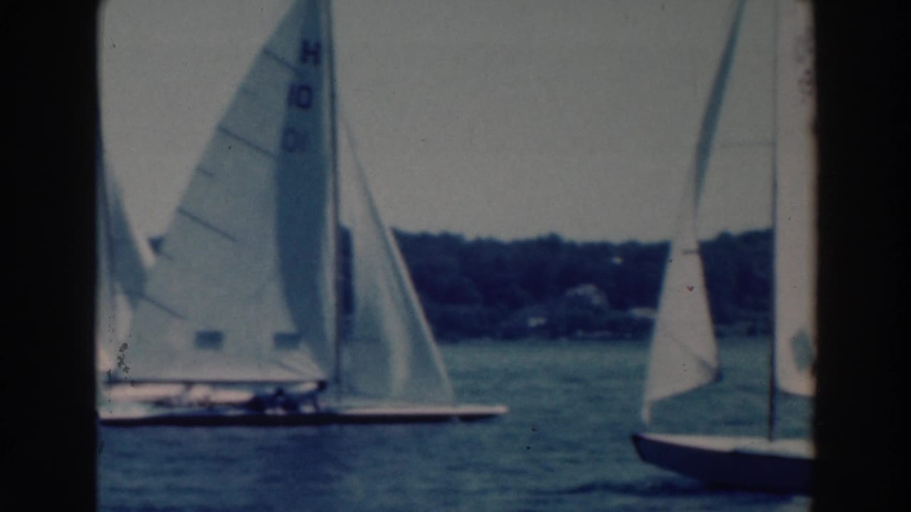 1964 Wisconsin home-movie frame of sailboats maneuvering close together, with sail markings visible.