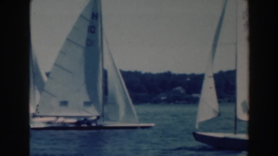1964 Wisconsin home-movie frame of sailboats maneuvering close together, with sail markings visible.