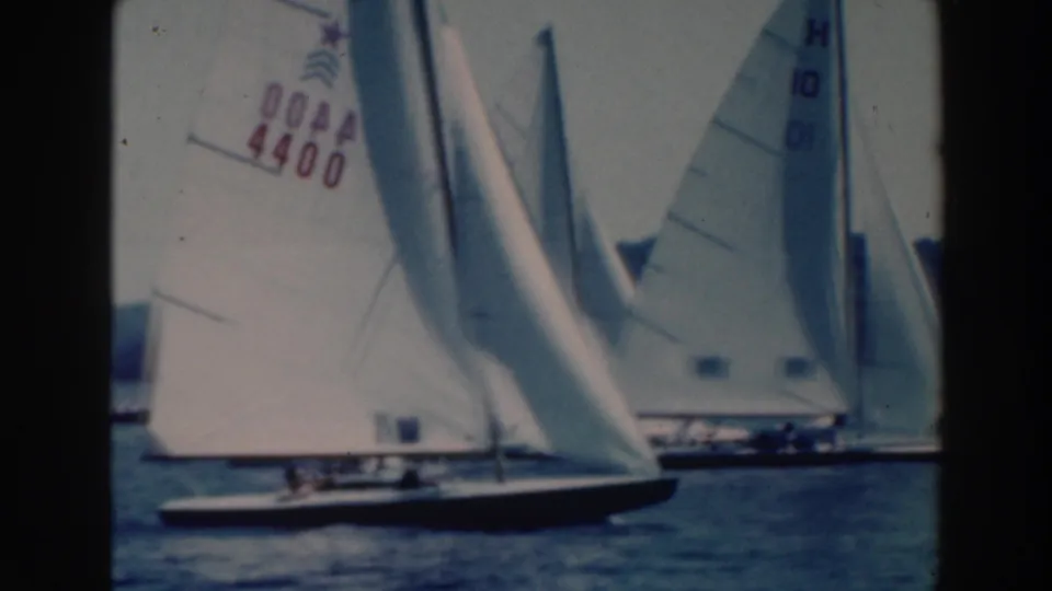 1964 Wisconsin 8mm frame with overlapping sailboats, including a sail marked 4400, on a calm lake.