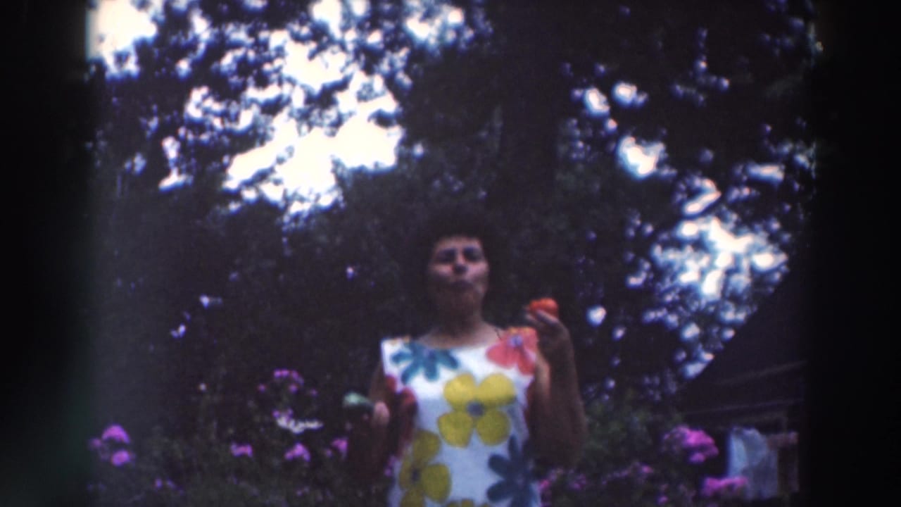 Woman in a white floral dress holding vegetables in a garden.