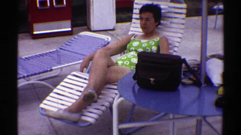 A 1969 Nebraska poolside frame shows the woman seated back on a striped lounge chair, with vintage patio furniture around her.