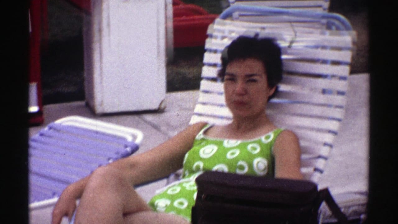Closer view of a woman in green swimwear sitting on a white poolside lounge chair.