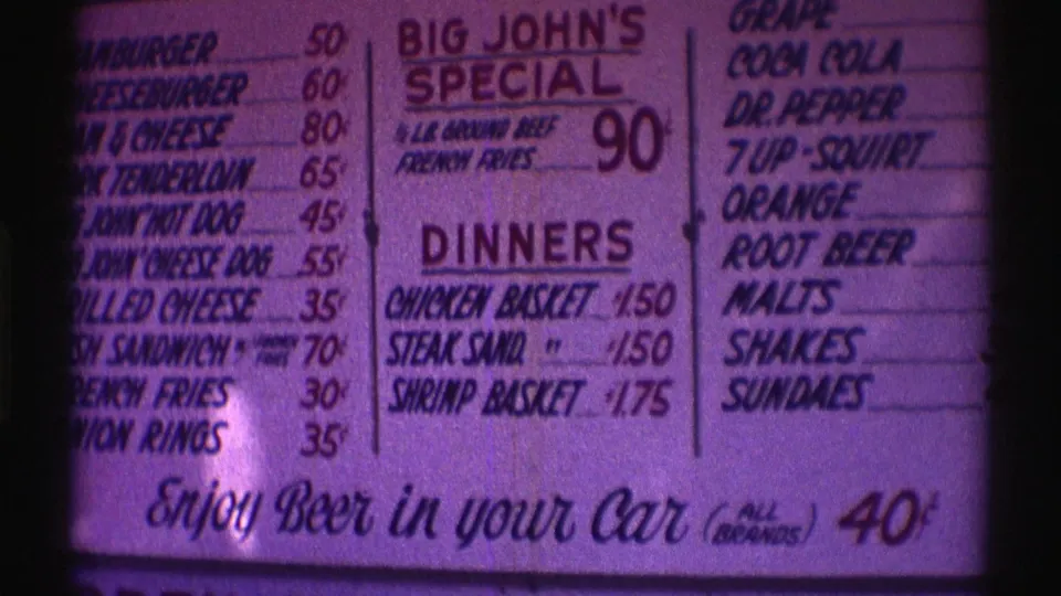 1969 Nebraska fast food menu frame showing price columns, dinner items, beverages, and the bottom beer-in-car slogan.