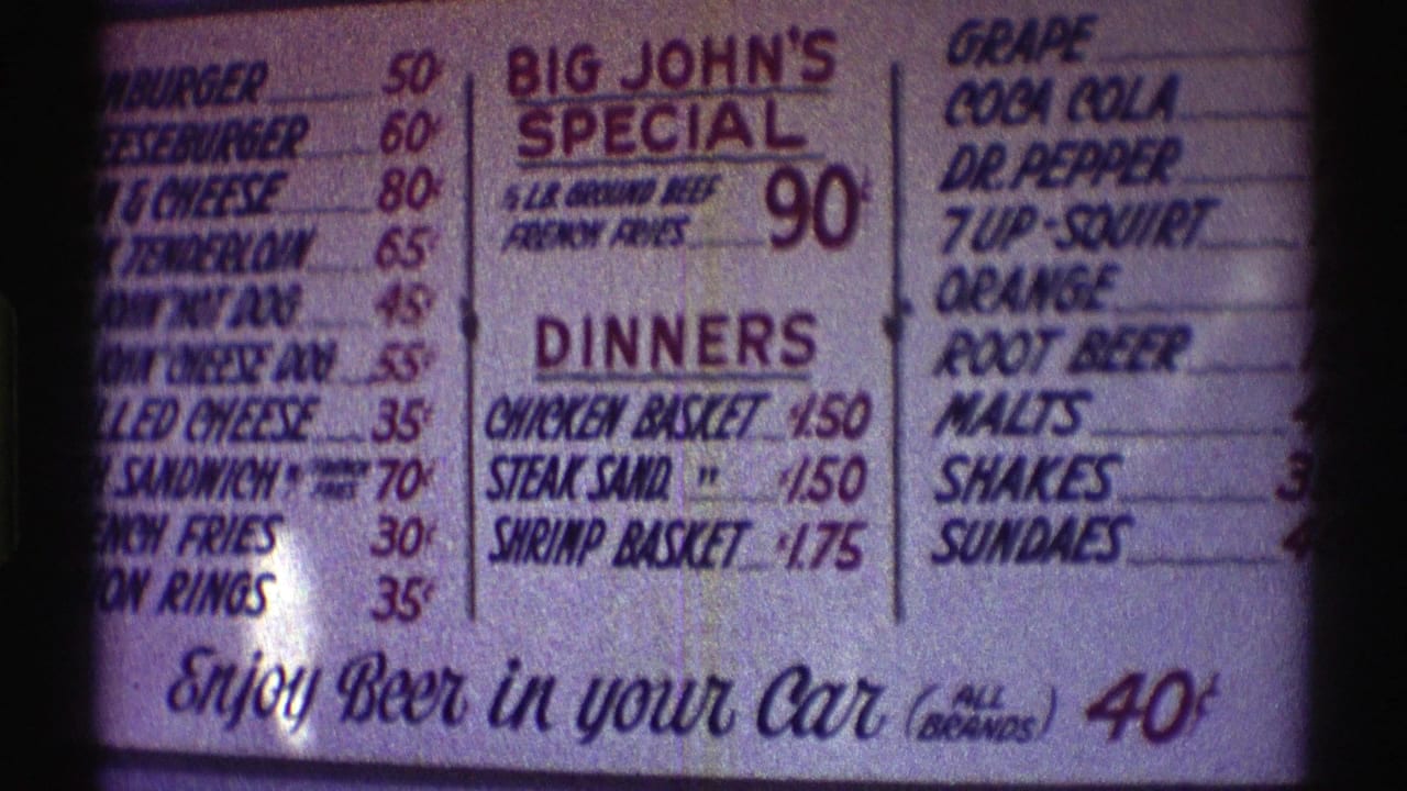 Close-up of a restaurant menu board with burgers, dinners, drinks, and beer-in-car pricing.