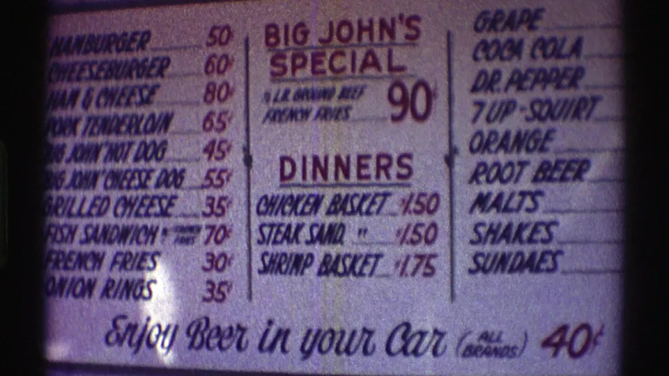 1969 Nebraska frame of the menu board emphasizing Big John's Special, chicken and shrimp baskets, soft drinks, and beer in your car for 40 cents.