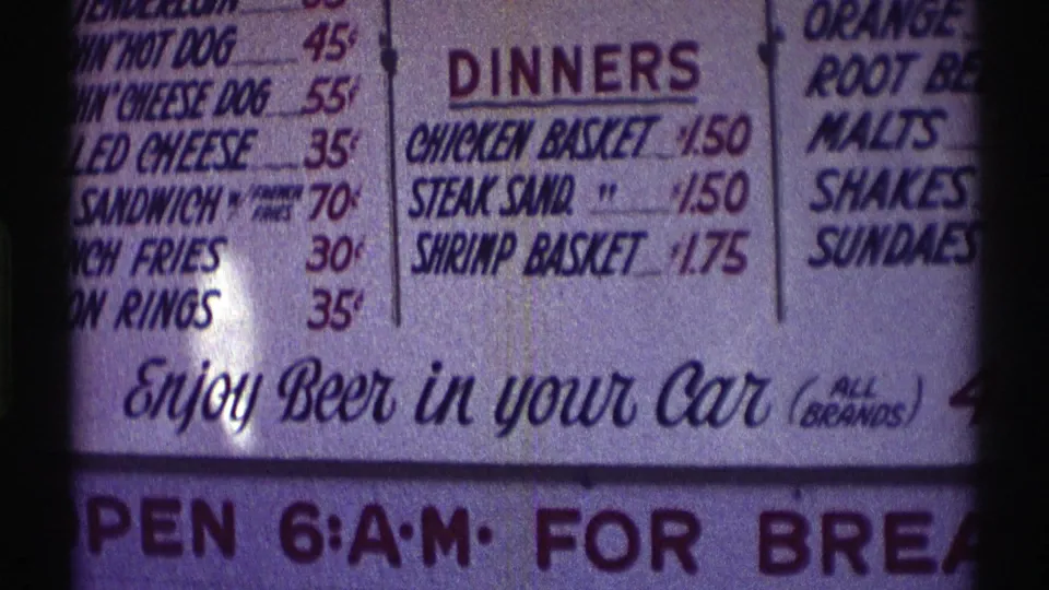 1969 Nebraska 8mm frame cropped on the dinners section, drink listings, and lower sign text advertising beer in your car.