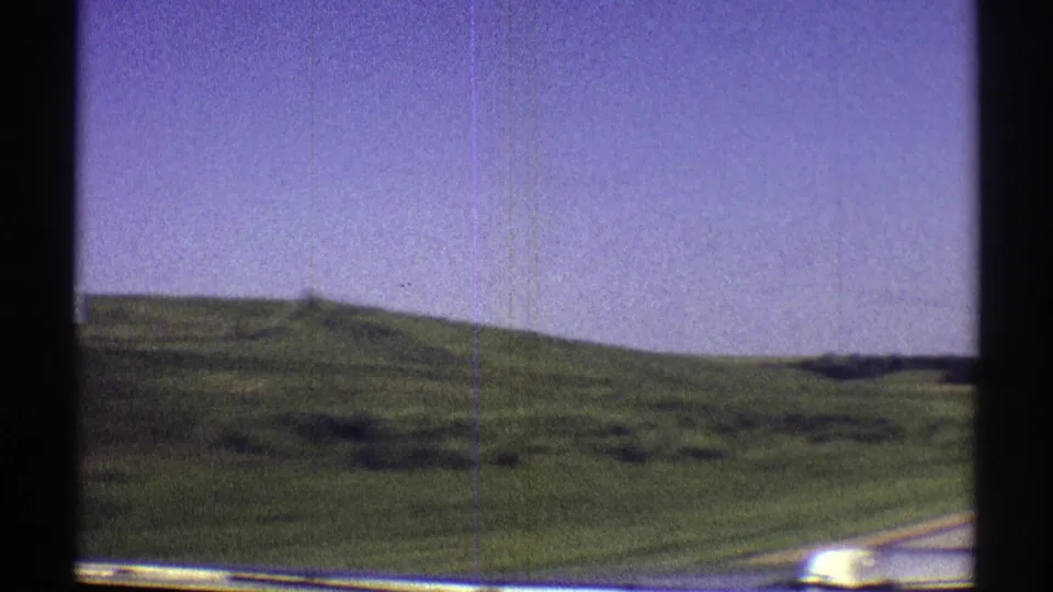 1969 Nebraska home-movie view of low green hills and open fields passing outside a car window.