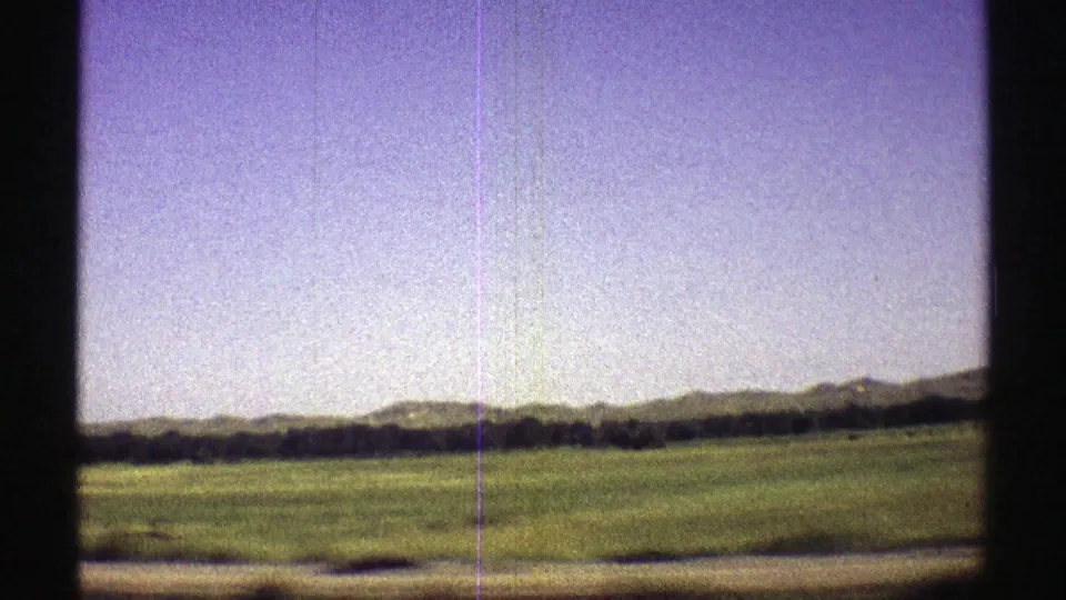 1969 Nebraska 8mm frame of open prairie and a distant ridge line, with visible scratches and grain from the film scan.
