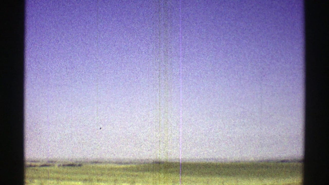 Low farmland horizon beneath a wide pale blue-purple sky.