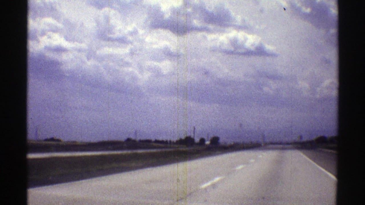 Wide empty highway under a cloudy sky, seen through a film contact-sheet frame.