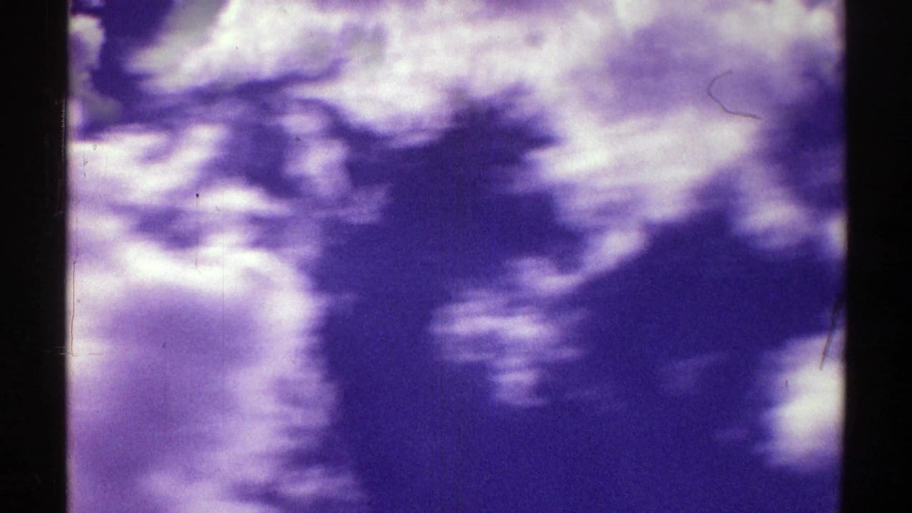 Purple-gray sky and soft cloud shapes in 1969 8mm Nebraska home-movie footage, with dark frame edges and visible film wear.