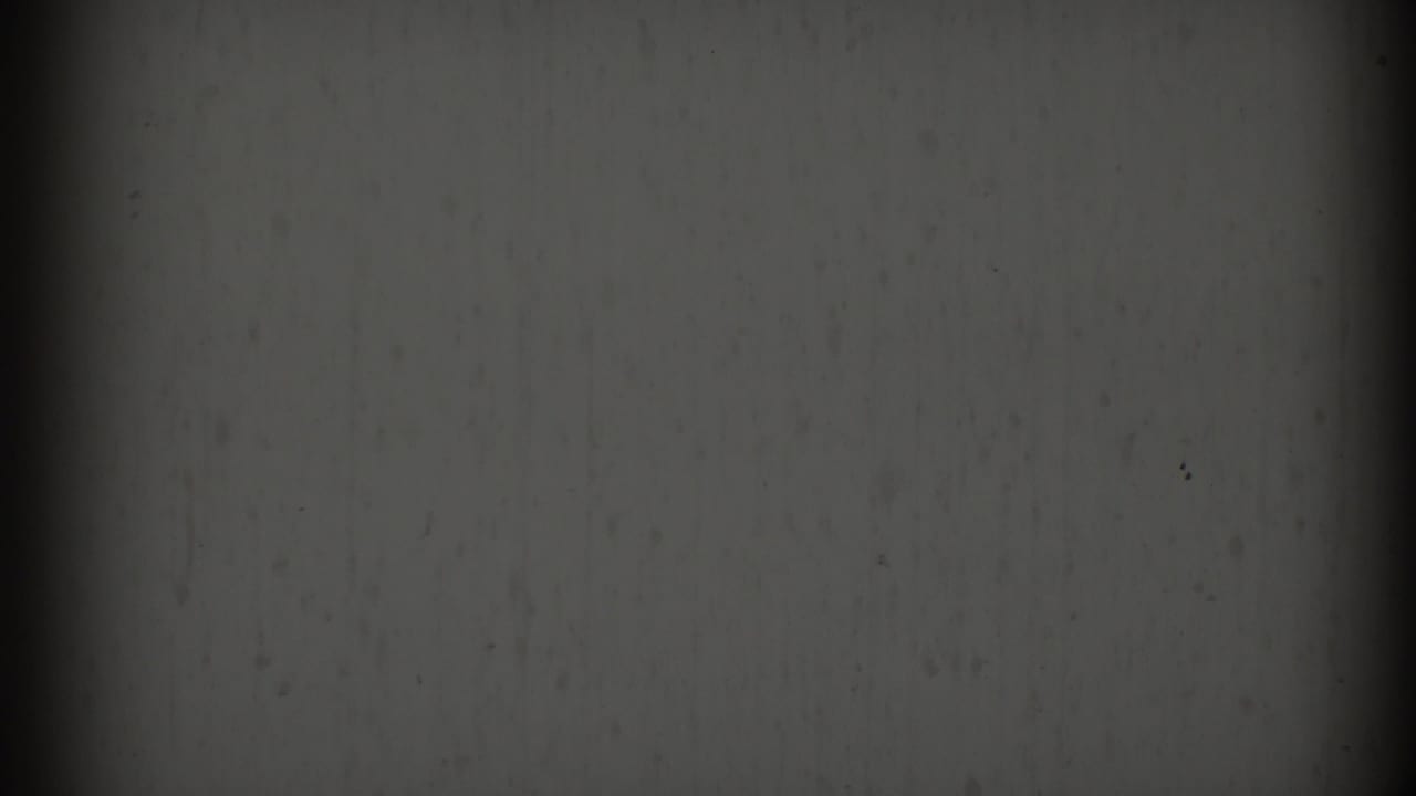 Gray film texture with dark vertical bands, grain, and small specks.