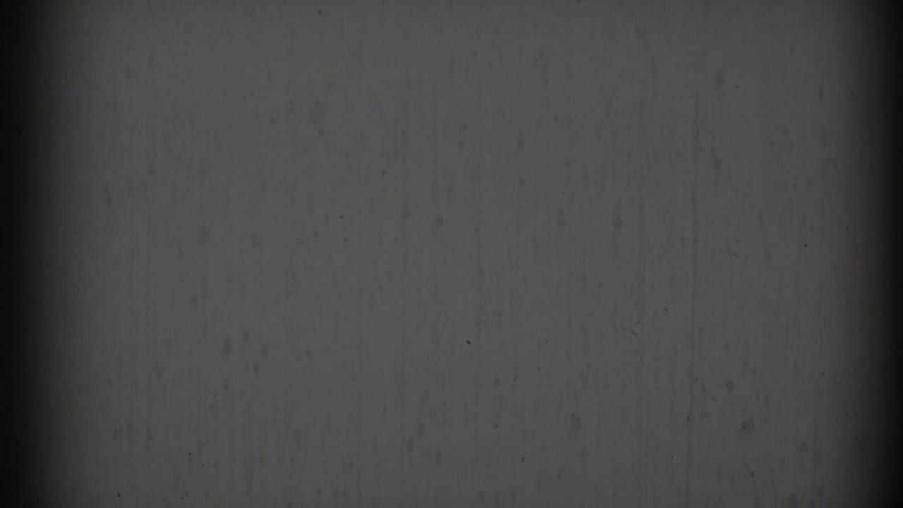 Dark, partially obscured interior wall and film edge with little subject detail visible.