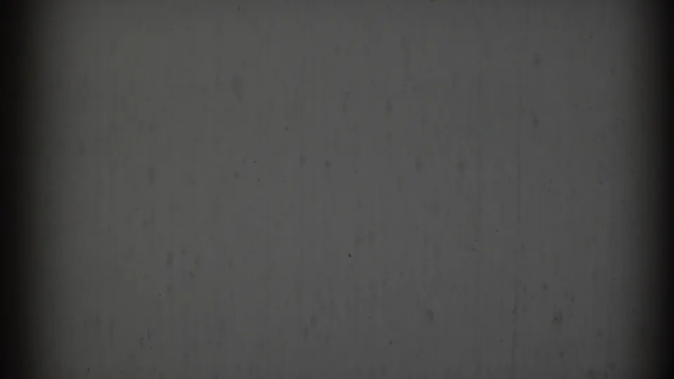A dim 8mm frame from the 1969 Clarendon Hills clip shows mostly wall surface, gate shadow, scratches, and partial film framing.