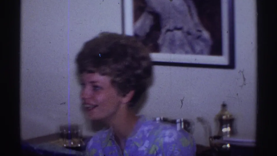 The woman turns toward someone off camera, smiling in a Clarendon Hills home interior with a framed picture and serving pieces behind her.