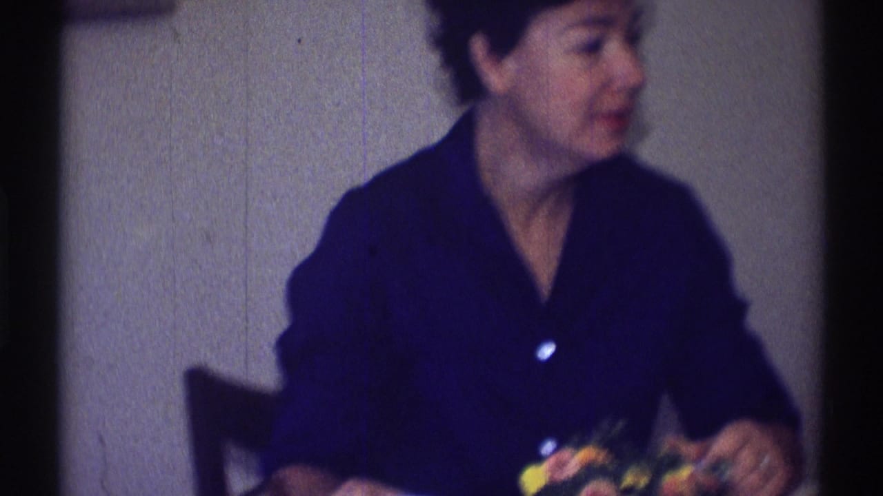 Woman in a dark blue shirt seated at a table with colorful items near her hands.