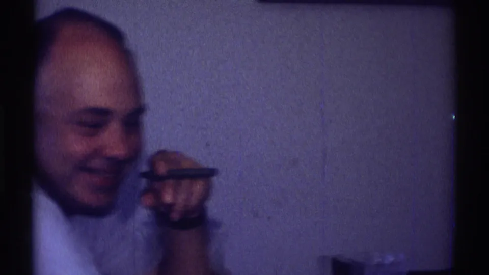 A seated man in a light shirt smiles while holding a cigar near his face inside the Clarendon Hills home interior.