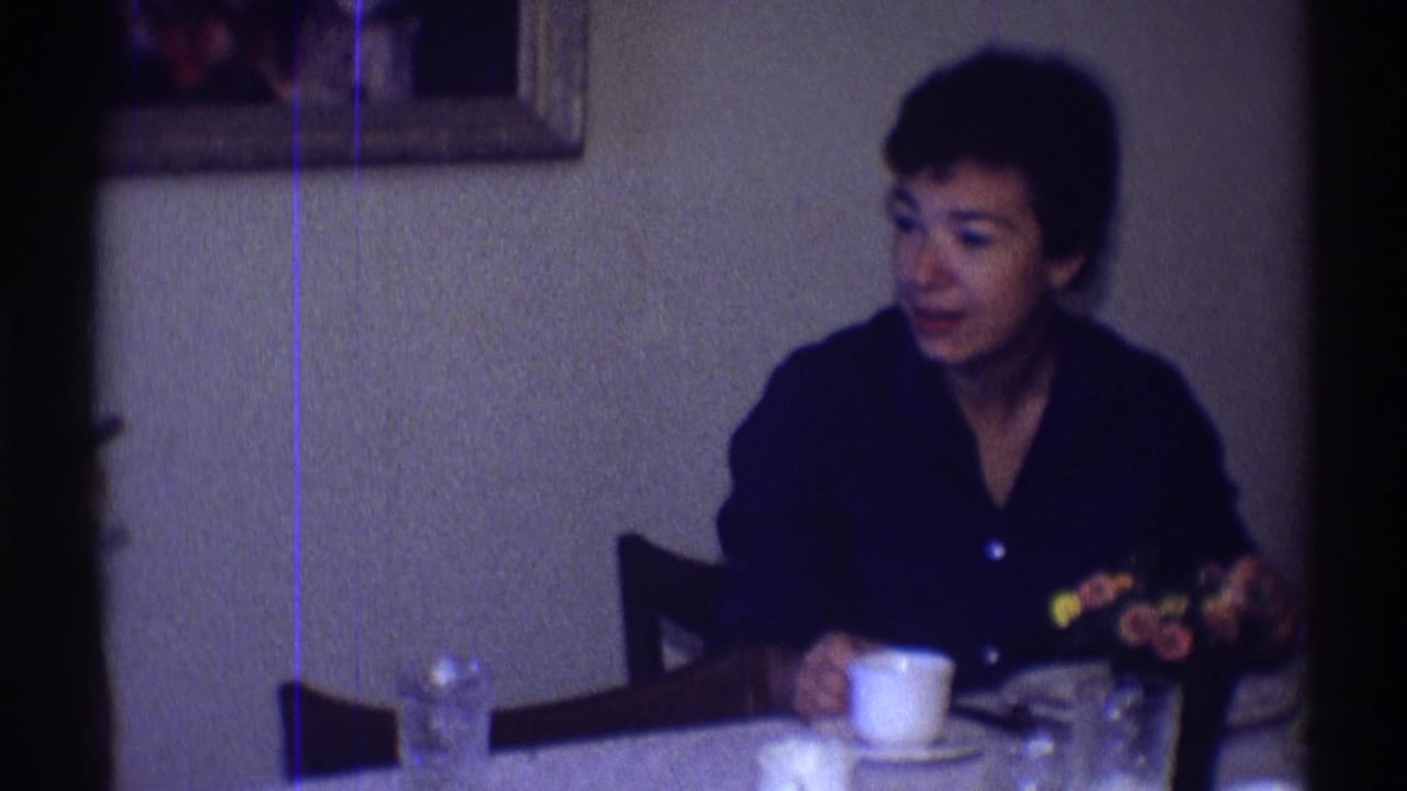 A woman sits at a table in a Clarendon Hills interior, with coffee cup, glassware, flowers, and framed wall pictures visible.