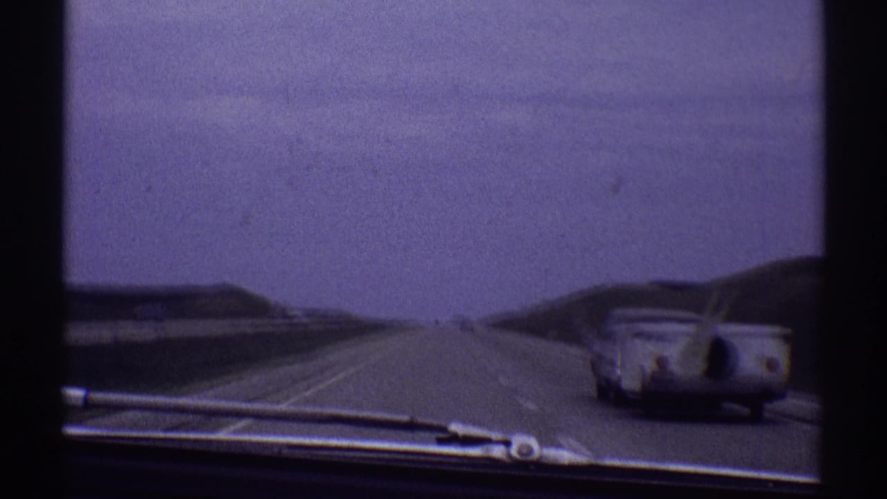 1969 8mm windshield view in Clarendon Hills, Illinois, showing a grey car towing a white trailer on a multi-lane highway.