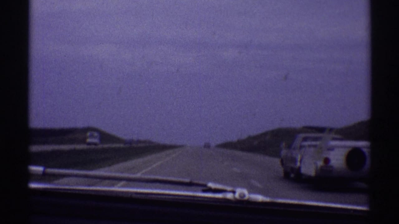 Highway view through a windshield with the towing car near the right edge.