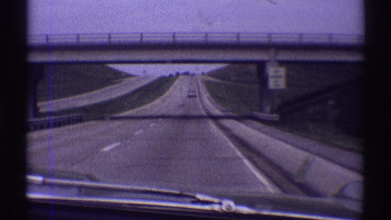 1969 8mm windshield view from a car on a highway near Clarendon Hills, Illinois, approaching and passing under a concrete overpass.