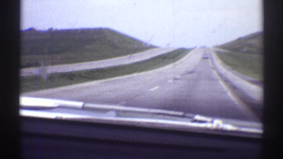 1969 8mm car-window view of an open multi-lane highway near Clarendon Hills, Illinois, with a distant vehicle ahead.