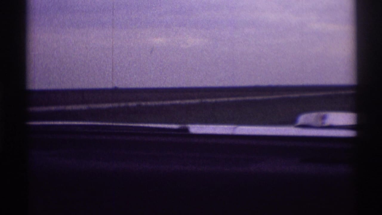 Close windshield view with wiper blade, dashboard edge, and pale sky.