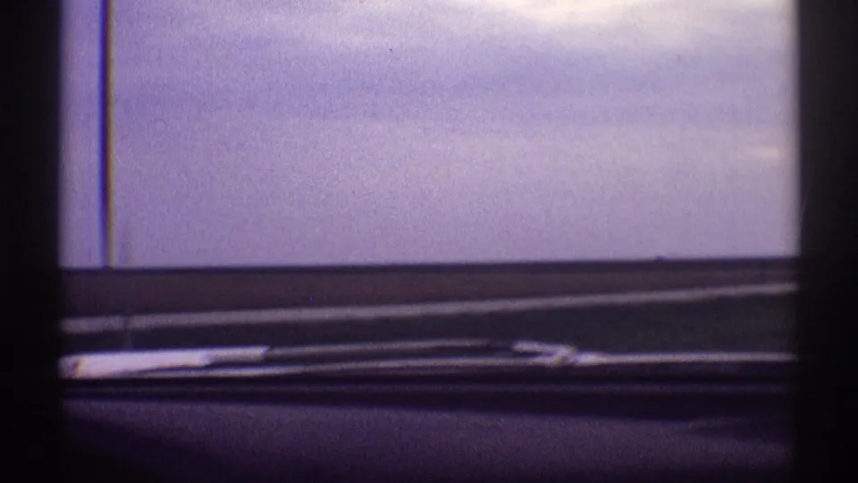 1969 Illinois road-trip frame showing an empty rural roadway through a car windshield with wipers at the base.