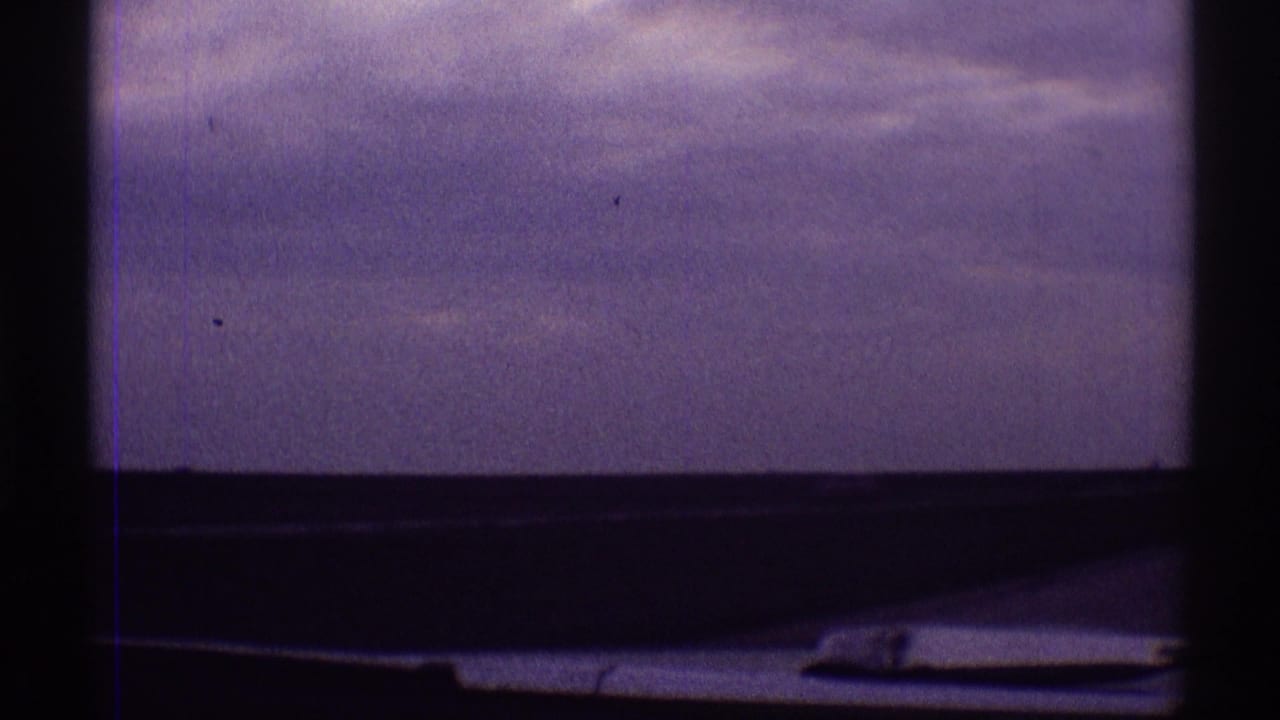 Clouded sky through a vehicle window with dark frame edges and a wiper or trim piece below.