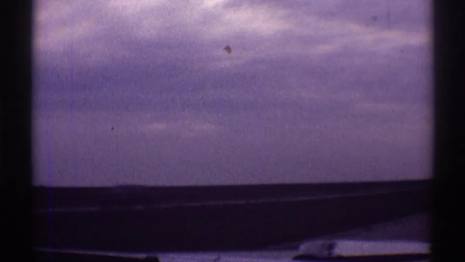 8mm home-movie view of purple-gray sky through a car window in Clarendon Hills, Illinois, with dark trim crossing the lower frame.