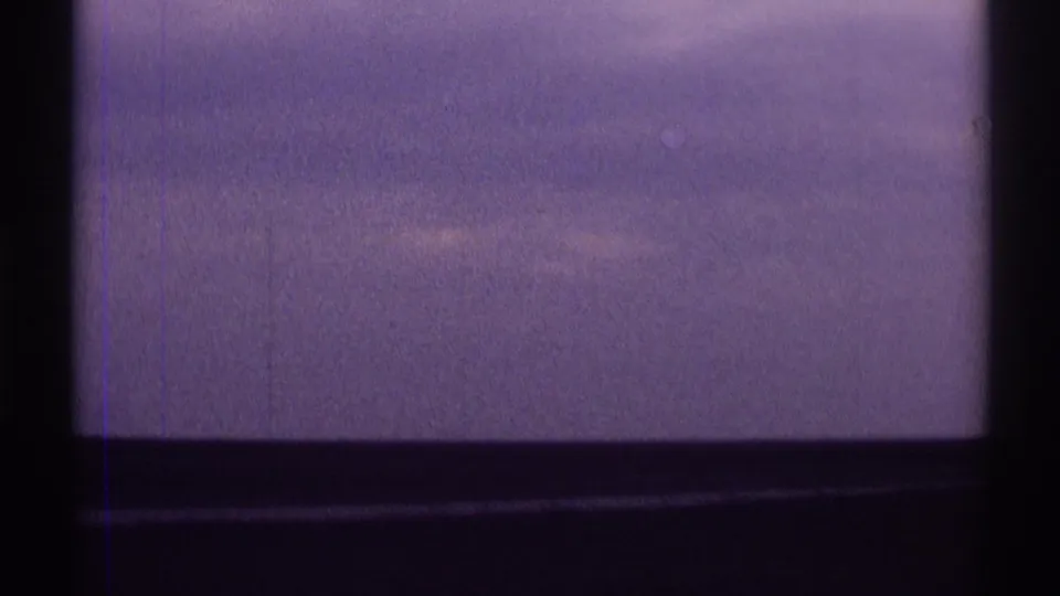 Final 1969 car-window frame showing an overcast Illinois sky, dark vehicle framing, and visible 8mm grain and color shift.