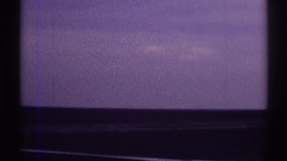 1969 8mm home-movie frame from Clarendon Hills showing hazy sky through dark vehicle or window framing, with visible film grain.