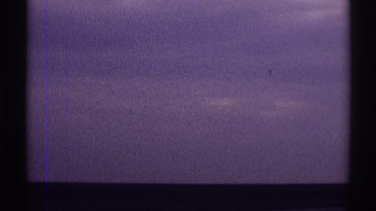 Purple-tinted cloudy sky seen through dark window or frame bars.