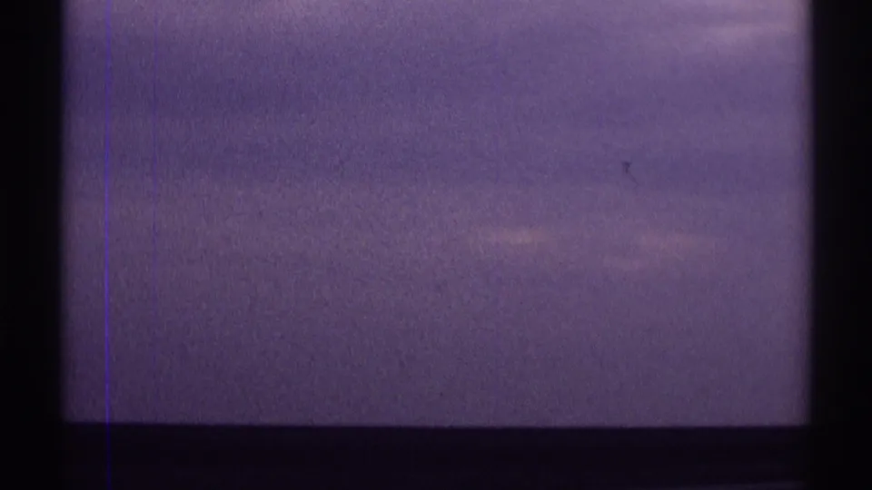 Purple-tinted sky and clouds viewed through dark interior framing in 1969 8mm home-movie footage from Clarendon Hills, Illinois metadata.