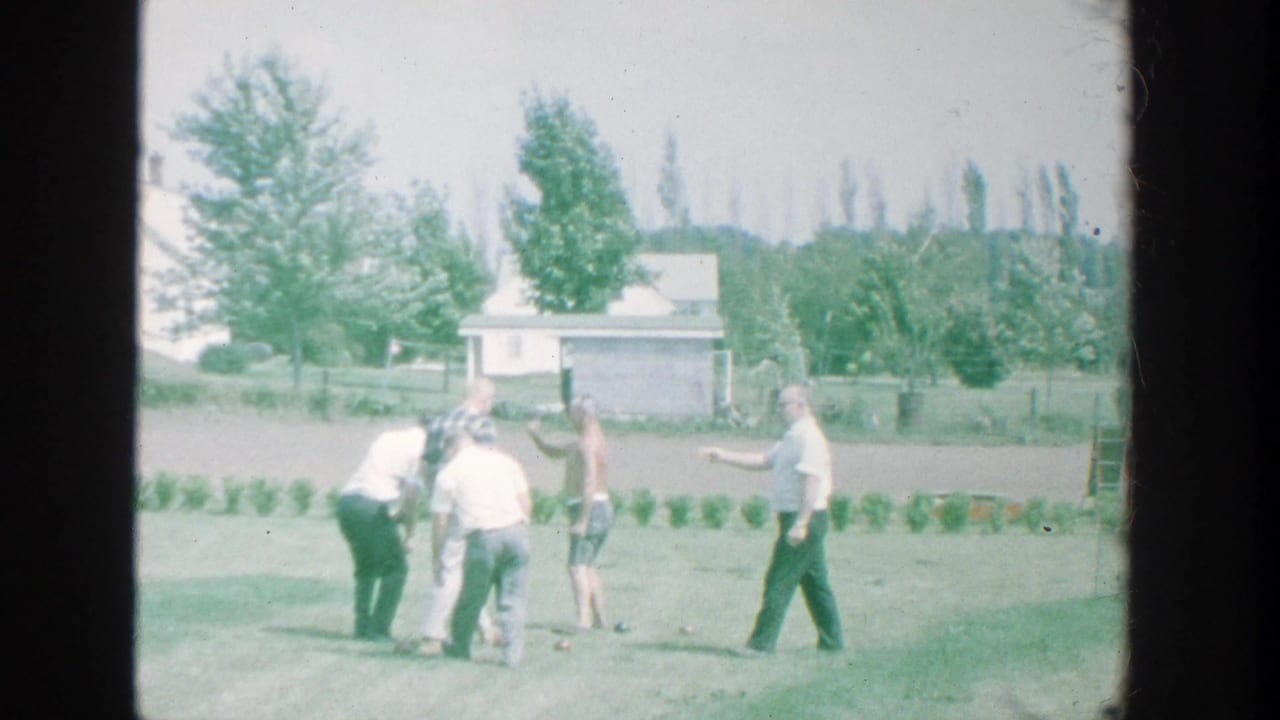 1964 Michigan backyard bocce scene with men bending and standing around the balls in bright daylight.