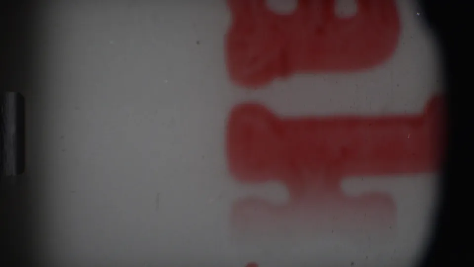 1969 Angola-attributed 8mm frame with blurred red block-like markings near the right side and visible grain, dust, and edge darkening.