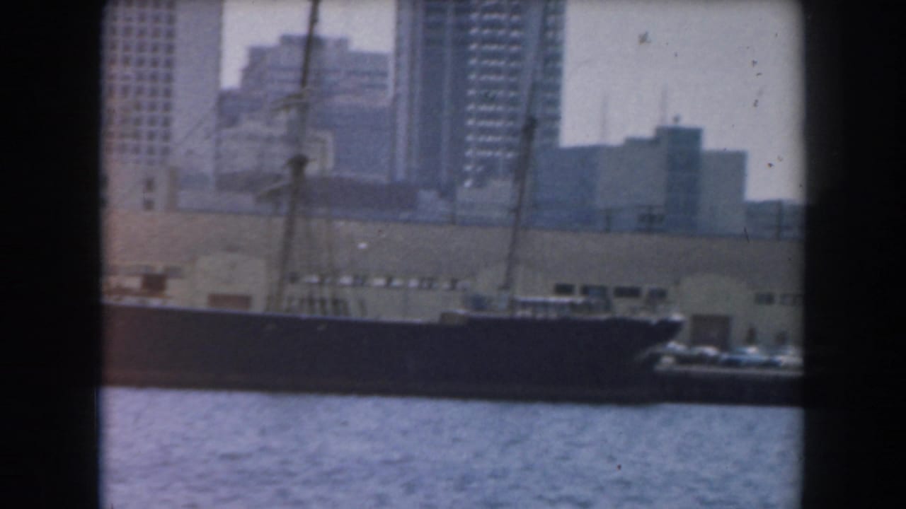 Large ship along the waterfront with city buildings rising behind it.