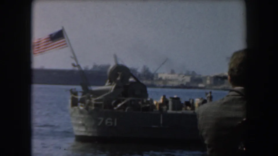 1961 California harbor view of a small military craft marked 761 flying an American flag, with a suited spectator partly visible at right.
