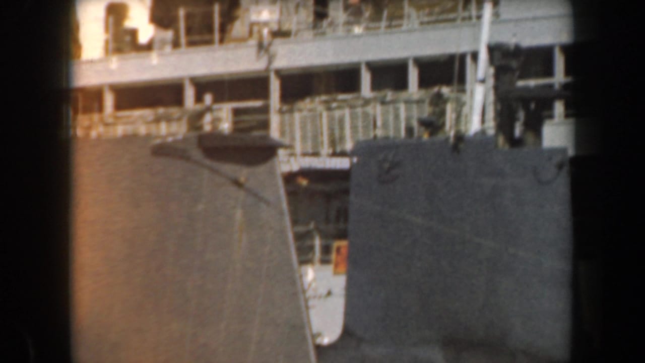 1961 California home-movie frame showing dark naval ship hulls, railings, and upper deck details in soft 8mm color.