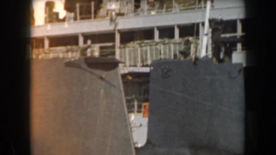 1961 California home-movie frame showing dark naval ship hulls, railings, and upper deck details in soft 8mm color.