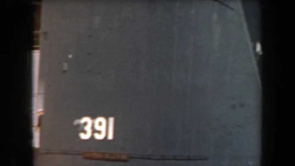 1961 California home-movie frame centered on a dark naval hull marked with the number 391.