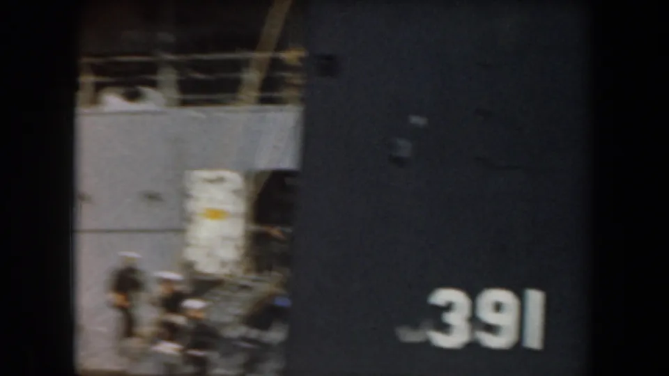 1961 California frame with a cropped grey naval vessel, deck area, and large white hull number 391 visible along the right side.