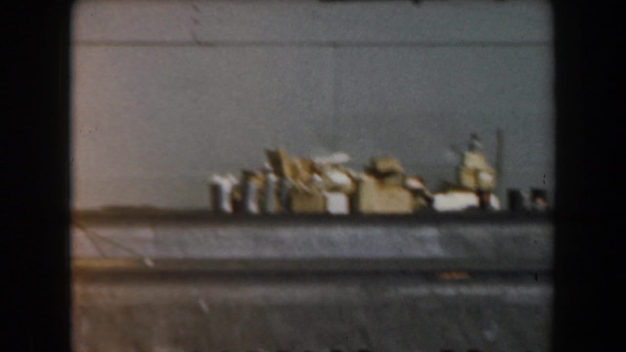 1961 California 8mm frame showing a small grey boat passing close by, with indistinct deck gear and soft film grain.