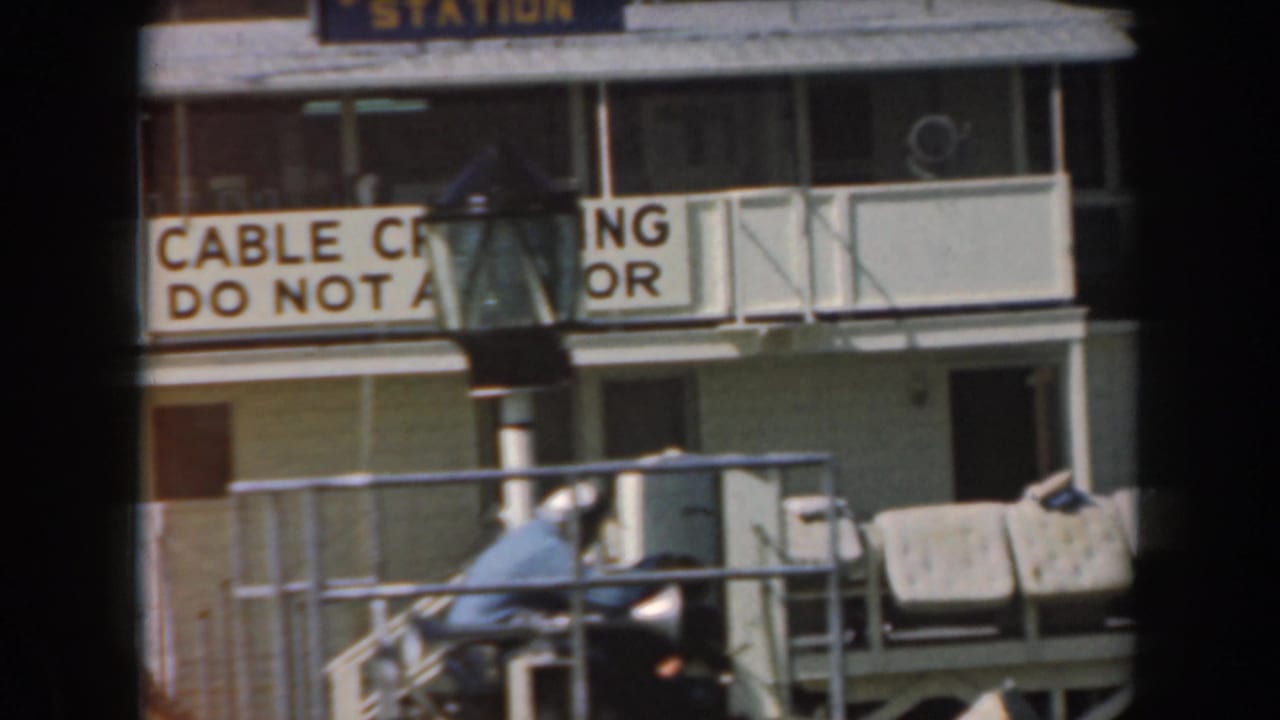 Naval station building with cable crossing warning sign and small boat at dock.